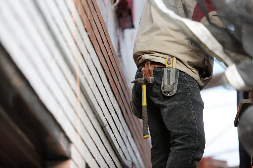 pexels-photo Close-up of a construction worker with hammer and tools, focused on the job.