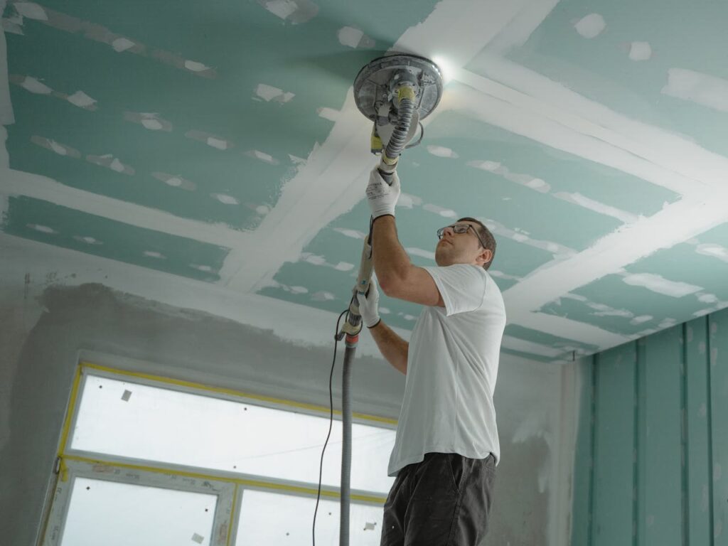 pexels-photo-6474343 A professional worker sanding the ceiling during a home renovation project. Indoor construction setting.
